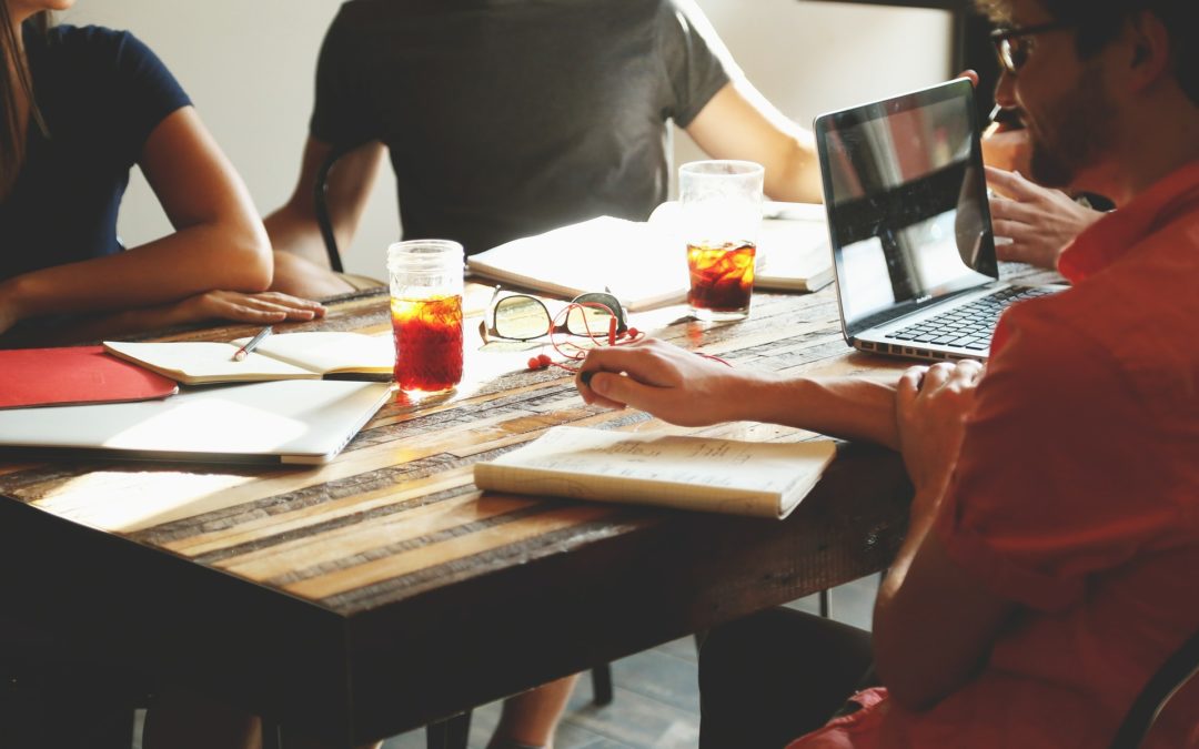 Three people engaging in internal communications around a table