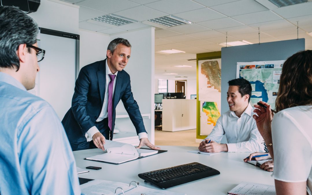 Man leading group discussion around a conference room table