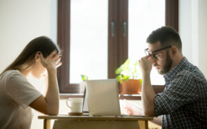 Two employees sitting at table showing signs of information overload