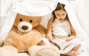 Little girl storytelling to a bear